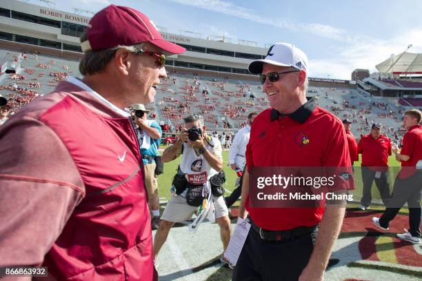 Head coach Jimbo Fisher of the Florida State Seminoles and head coach Bobby Petrino of the Louisville Cardinals speak to each other prior to their...