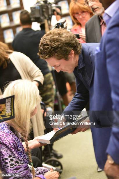Televangelist Joel Osteen signs a book for a fan during a book signing for his book "Blessed in the Darkness" at Barnes & Noble at The Grove on...