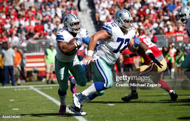 Ezekiel Elliott of the Dallas Cowboys rushes behind Travis Frederick during the game against the San Francisco 49ers at Levi's Stadium on October 22,...