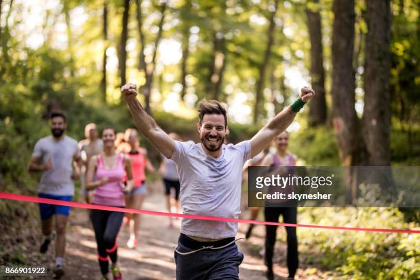 felice maratoneta vincendo e incrociando il traguardo con le braccia alzate. - 10000 metri foto e immagini stock