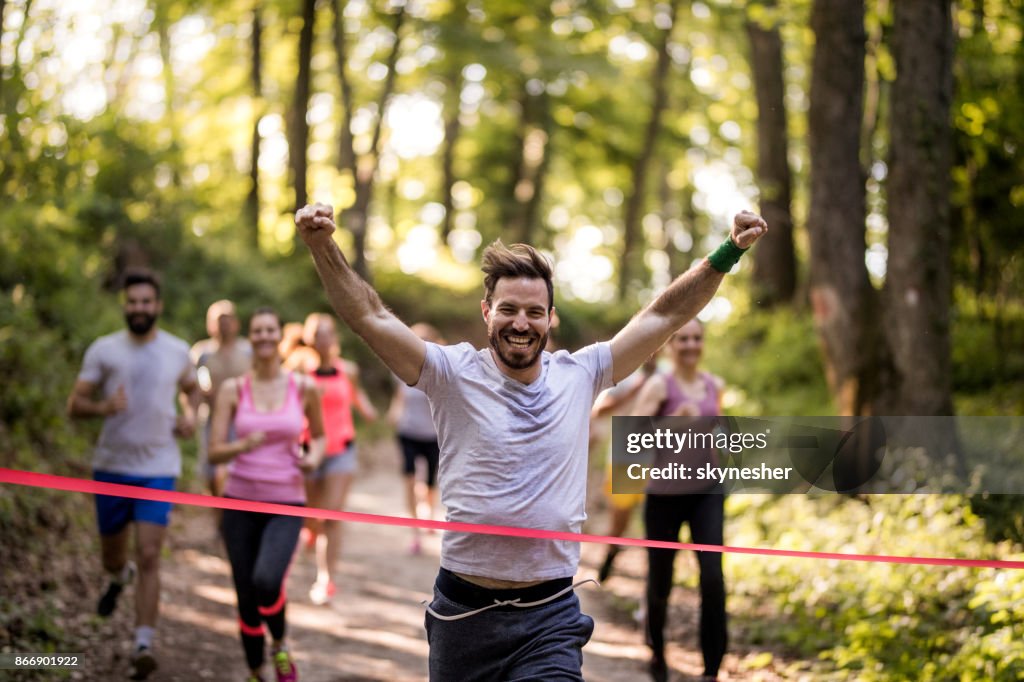 Lycklig marathon löpare vinna och korsa mållinjen med höjde armarna.