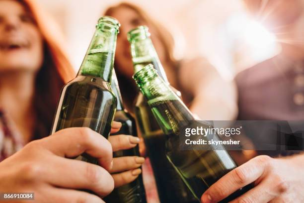 close up of unrecognizable people toasting with beer. - beer bottles stock pictures, royalty-free photos & images