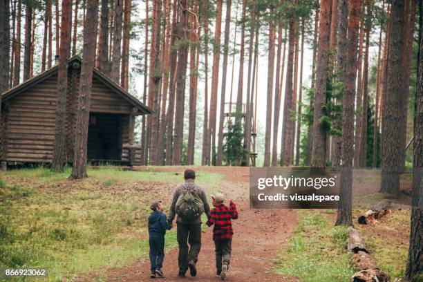 father with his two sons going to log cabin - cabin stock pictures, royalty-free photos & images