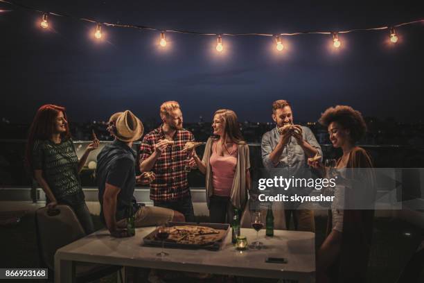 gruppo di amici felici che mangiano pizza a una cena sul balcone dell'attico. - rooftop dining foto e immagini stock