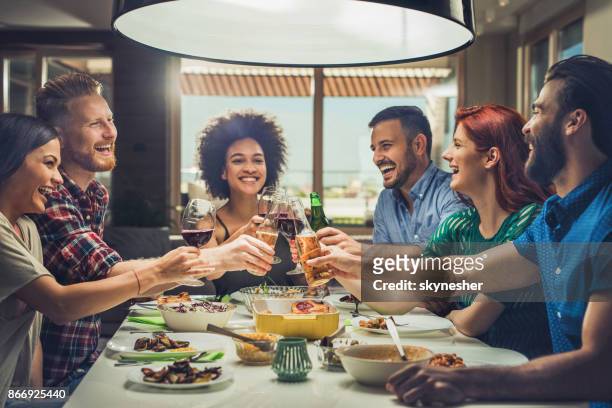 group of happy friends toasting while eating at dining table. - dinner party stock pictures, royalty-free photos & images