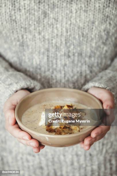 woman holding bowl with creamy mushroom and white bean soup - porcini mushroom stock pictures, royalty-free photos & images