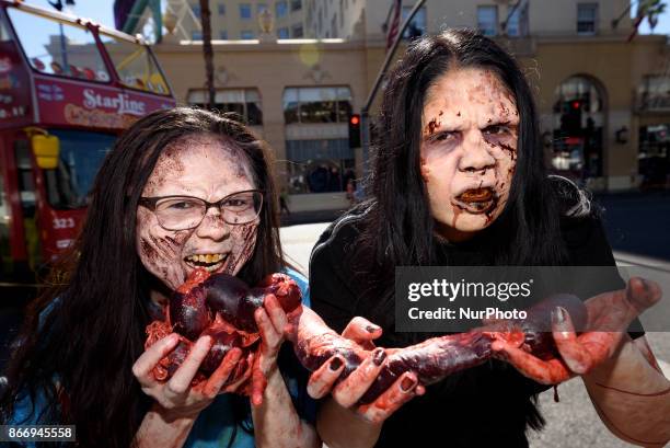 Animal rights activists dressed as zombies pretend to eat human meat during a Halloween campaign against meat consumption in Los Angeles, California...