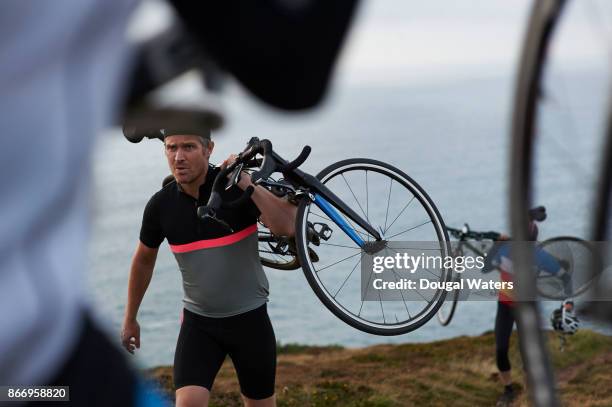 cyclists carrying bikes along coastal path. - group selective focus stock pictures, royalty-free photos & images