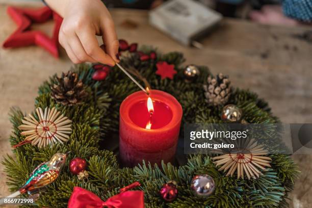 little girls hand lighting candel of advent wreath - advent wreath stock pictures, royalty-free photos & images