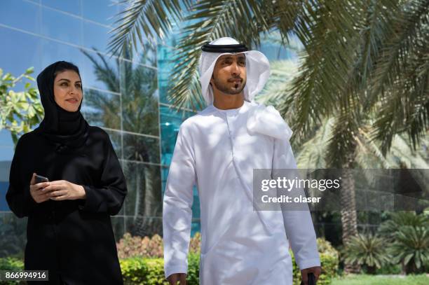 arab businessmen and woman having conversation, walking in internet city - lypseuae2015 stock pictures, royalty-free photos & images