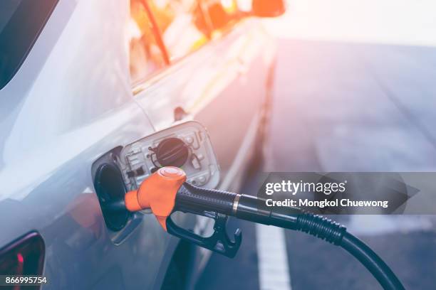 gas nozzle pumping gas into a gray blonde car to fill the machine with fuel. gas station pump. - benzine stock pictures, royalty-free photos & images