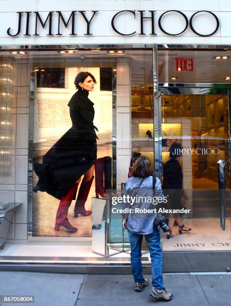 Tourist peers into the window of the Jimmy Choo shoe store on Fifth Avenue in New York City. The designer footwear retailer is know for cutting-edge...