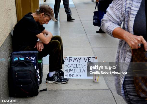 Man with a sign identifying himself as a homeless Army veteran asks for money as he sits on a New York City sidewalk.