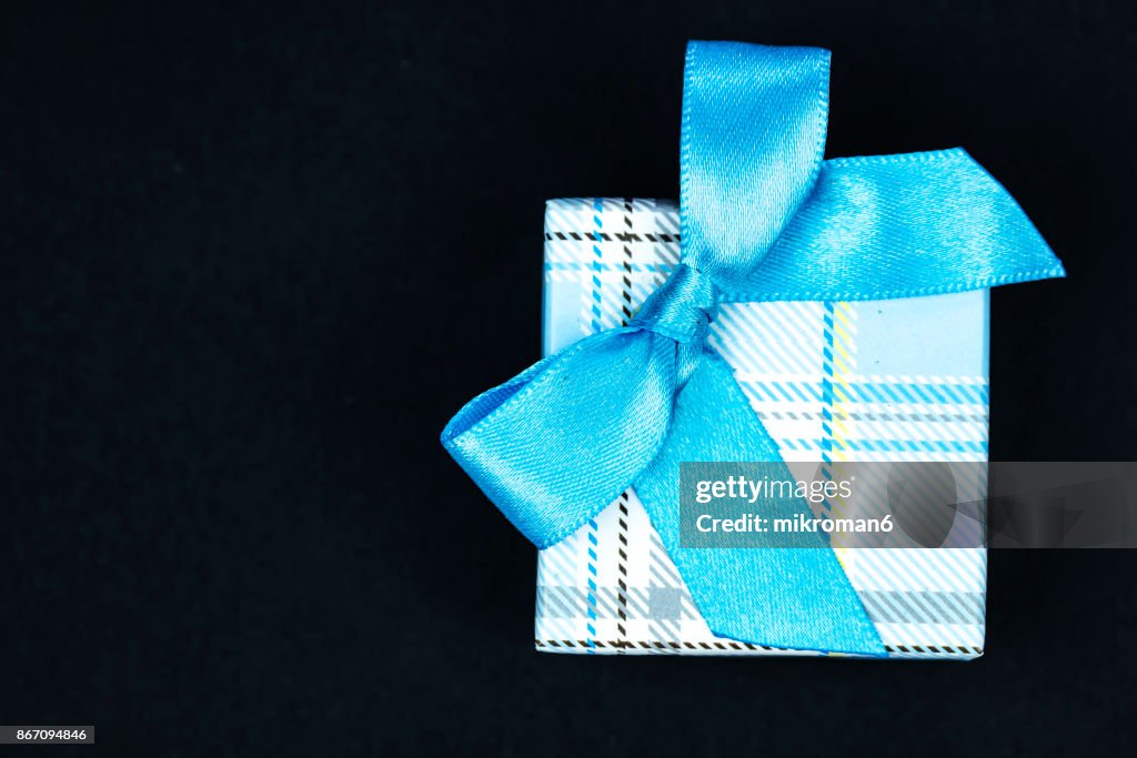 Directly Above Shot Of Gift Box With blue Ribbon on black background