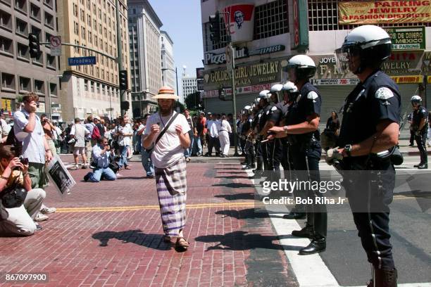 Protestors walk in front of a police line blocking the route to the Staples Center - the site of the Democratic National Convention, on August 13,...