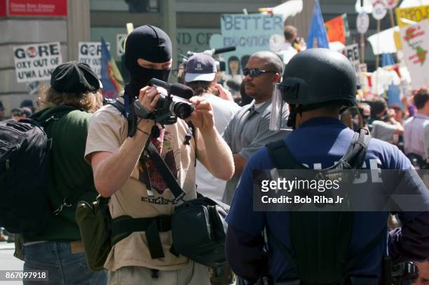 Hooded individual videotapes Los Angeles Police Department officers as they gathered near the Staples Center - site of the Democratic National...