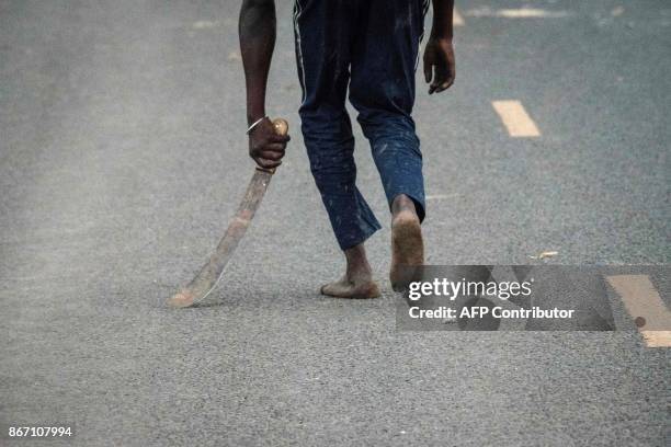 Supporter of National Super Alliance holding a machete reacts towards police officers during a protest against Kenya's second poll in Kisumu, on...