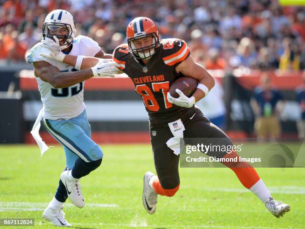 Tight end Seth DeValve of the Cleveland Browns stiff arms linebacker Wesley Woodyard of the Tennessee Titans, as he carries the ball downfield in the...