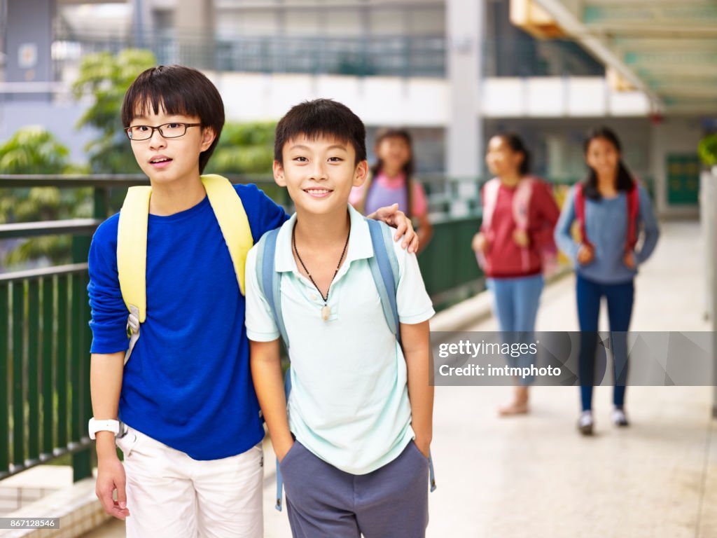 Aziatische elementaire schooljongens wandelen in school