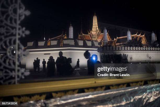 Mourners, reflected in a window, take photographs outside Wat Phra Kaew, or the Temple of the Emerald Buddha on October 27, 2017 in Bangkok,...