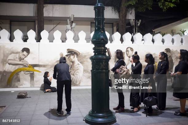 Mourners wait to have their photograph taken in front of a painting of the late Thai King Bhumibol Adulyadeja outside Wat Phra Kaew, or the Temple of...