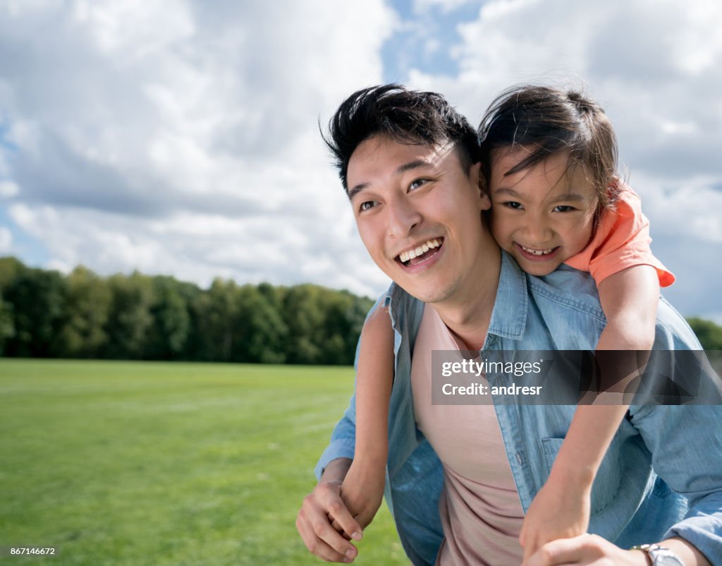 Asian father looking very happy playing with his daughter at the park