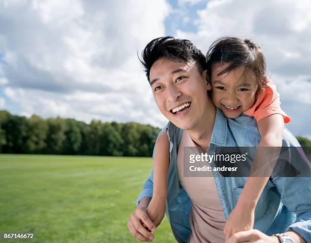 asian father looking very happy playing with his daughter at the park - asian father stock pictures, royalty-free photos & images