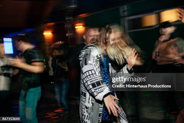 young woman dancing energetically at nightclub - bewegungsunschärfe mensch stock-fotos und bilder
