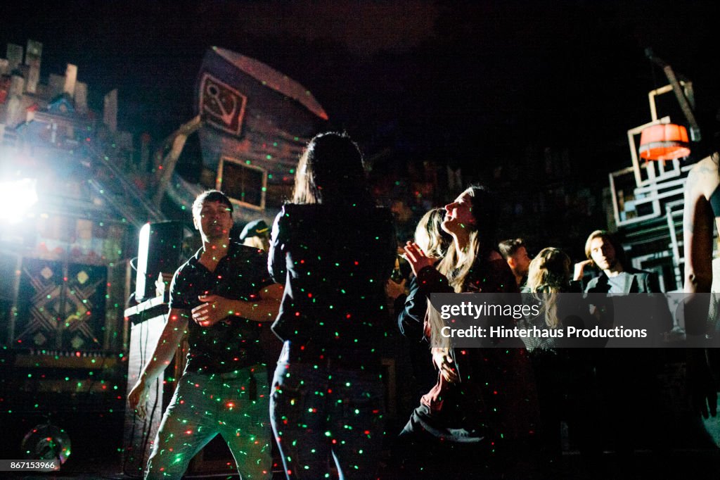 Group Of Partygoers Dancing While Being Lit By Lasers At Nightclub