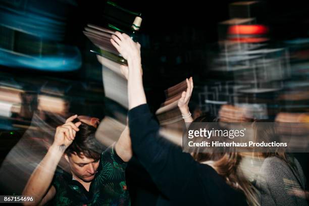 energetic scene of people on dancefloor at nightclub - fiesta fotografías e imágenes de stock
