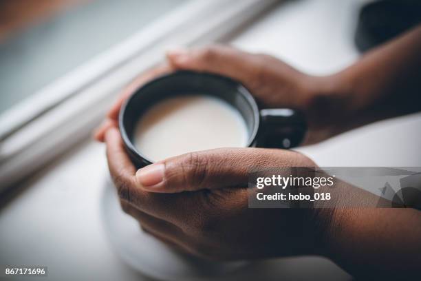 woman  holding cup of hot white chocolate beverage on white wooden background - black mug stock pictures, royalty-free photos & images