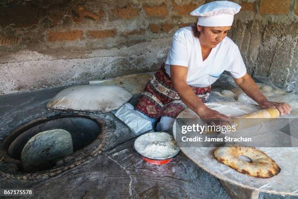 traditional breadmaker rolling lavash bread before placing into clay oven to bake, (smaller bread is bokon), yerevan, armenia (model release) - lavash stockfoto's en -beelden