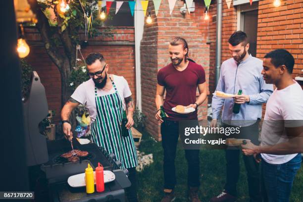 amigos en una barbacoa en el patio trasero - male burger eating fotografías e imágenes de stock