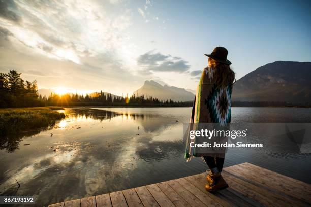 a female watching sunrise at a lake - canadian forest stock-fotos und bilder