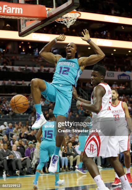 Clint Capela of the Houston Rockets watches as Dwight Howard of the Charlotte Hornets dunks the ball during their game at Spectrum Center on October...