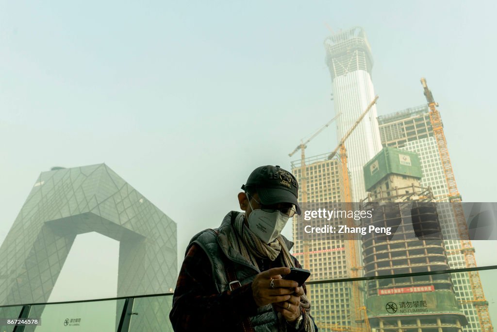 Man wearing mask walks in heavy haze at Beijing CBD.  A...