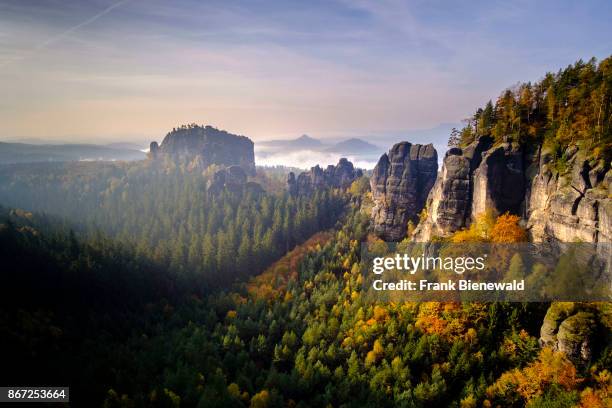 Landscape with the fog covered river Elbe valley, rock formations and the summit Rauschenstein at sunrise in autumn.