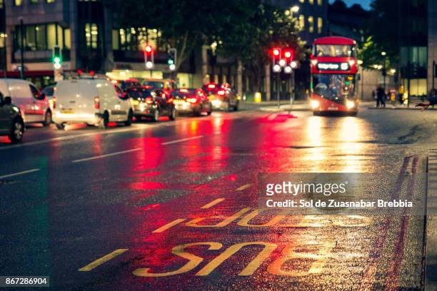 bus stop with defocused car lights in the background - london red bus photos et images de collection
