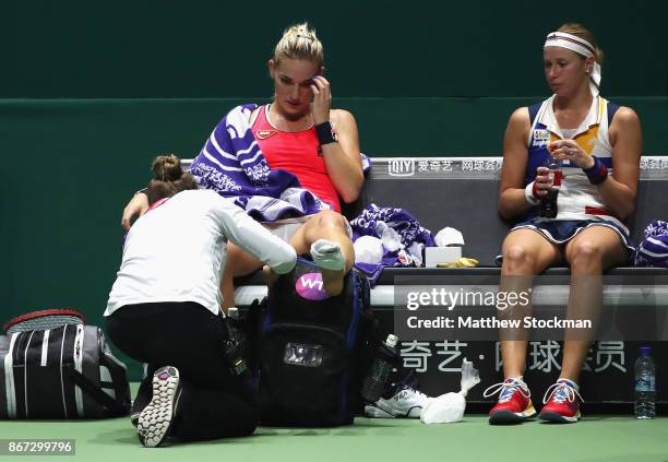 Timea Babos of Hungary has her ankle strapped after she slipped partnering Andrea Hlavackova of Czech Republic in the doubles semi final match...