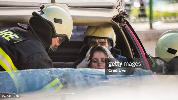 dos bomberos ayudando a conductor femenino - head injury fotografías e imágenes de stock