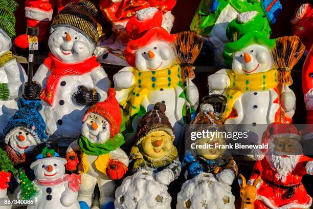 Colorfully painted little statues of snowman, made from clay.