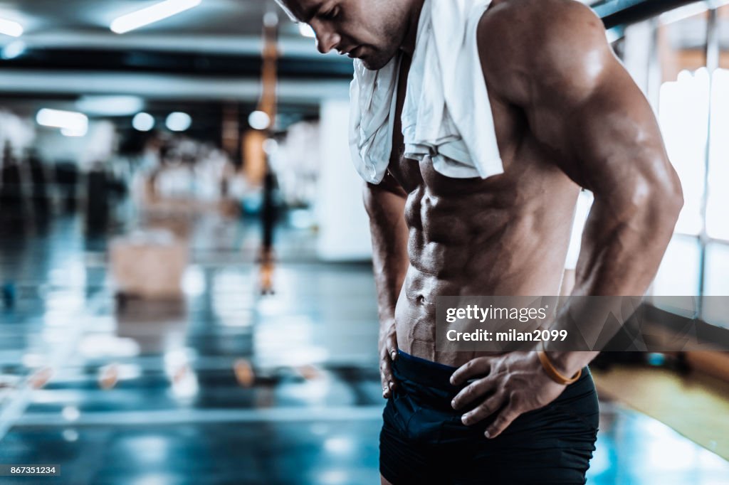 Young man tired after training showing his abdominal muscles