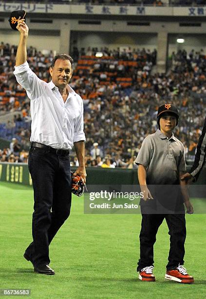 Actor Tom Hanks and Thomas Grazer gesture to the crowd during the ceremonial first pitch prior to the professional baseball match between Yomiuri...