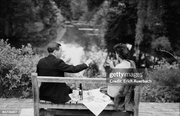 Smartly-dressed couple share a small bottle of champagne at the Glyndebourne opera festival in East Sussex, 28th May 1959.
