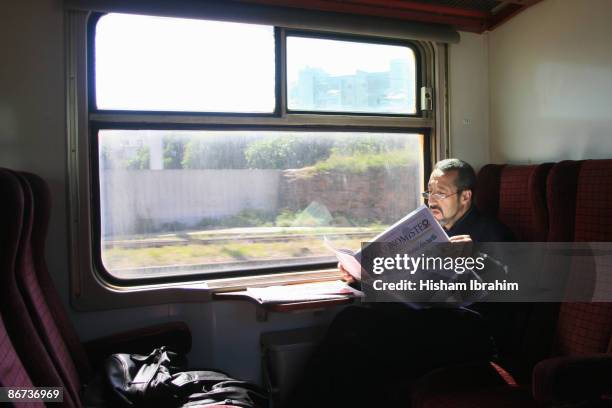 moroccan businessman reading newspaper on a train - escrita ocidental imagens e fotografias de stock