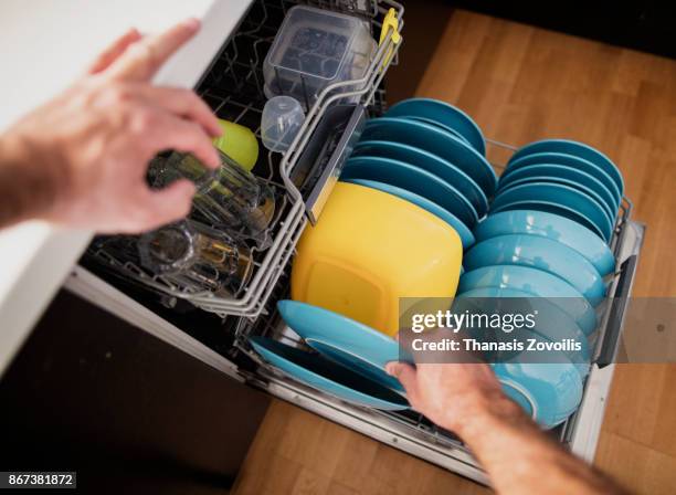 man arranging dishes in the dishwasher - loading dishwasher stock pictures, royalty-free photos & images