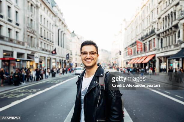 young happy smiling man in glasses on the streets of london, uk - en el centro fotografías e imágenes de stock