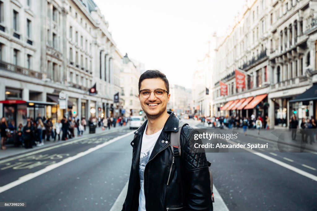 Young happy smiling man in glasses on the streets of London, UK