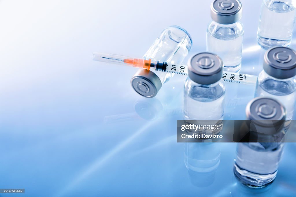 Vials and syringe on blue table top elevated