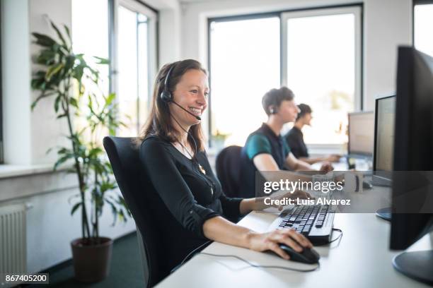 smiling customer service representative using computer - telefoonberoep stockfoto's en -beelden
